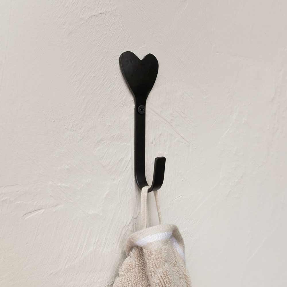 Ein schwarzer Bastion Collections - Wandhaken Herz schwarz mit einem daran hängenden Handtuch.