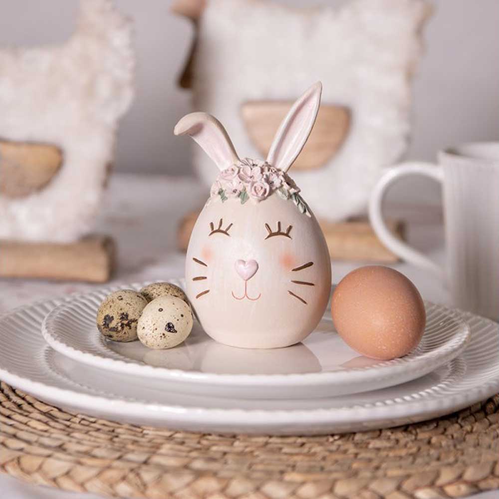 Eine Figur von Clayre & Eef – Hase als Osterei sitzt auf einem Teller neben Eiern.