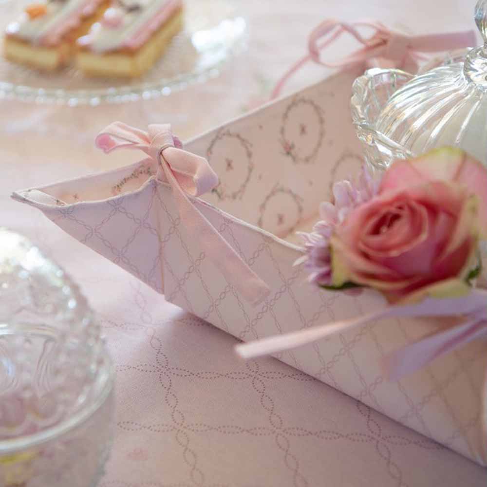 Ein rosa Clayre & Eef - Topflappen Hase Rosa mit Blumen und einem Glasgefäß auf einem Tisch.