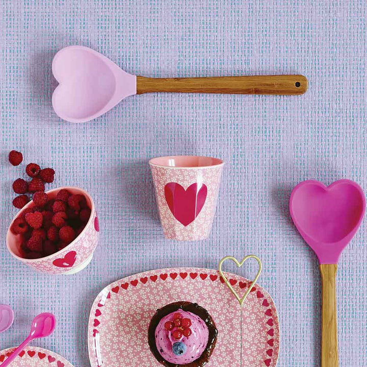 Eine rosa-weiße Tischdecke mit einem Cupcake und einem Reis-Kochlöffel in Herzform.