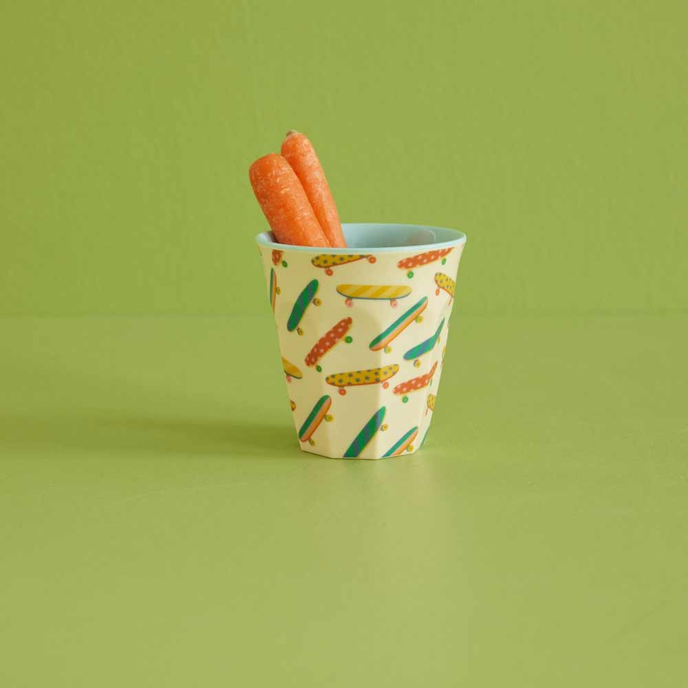 Satz mit Produktname: Zwei ganze Karotten in einem bunten Rice - Melamin Cup Skateboard Medium, vor einem hellgrünen Hintergrund.