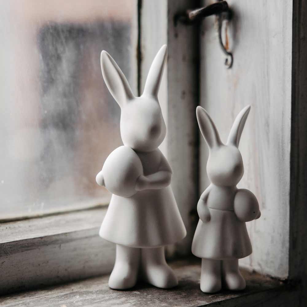 Zwei Storefactory - Ester Hase-Figuren auf einer Fensterbank.