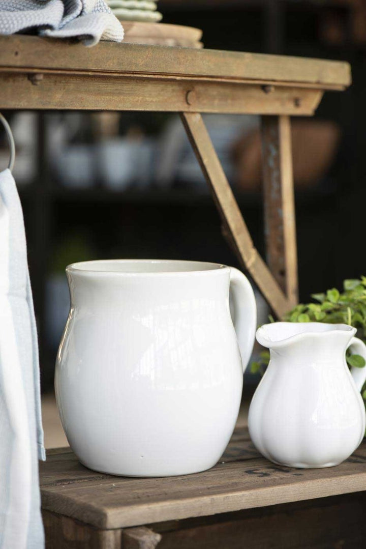 Eine große weiße Keramikkanne 2,5 Liter Mynte von Ib Laursen und eine kleinere Kanne auf einem Holztisch in rustikalem Ambiente.