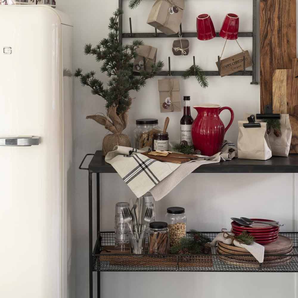 Eine gemütliche Küchenecke, dekoriert mit rustikalen Elementen, mit Regalen mit Geschirr, dem Ib Laursen - Krug Mynte 1,7 Liter, Gläsern und einem kleinen Weihnachtsbaum neben einem weißen Vintage-Kühlschrank.