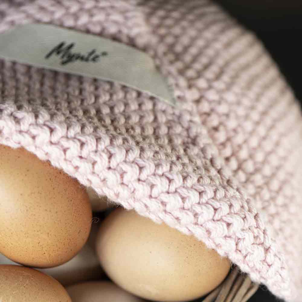 Nahaufnahme von braunen Eiern unter einer rosa Strickmütze mit einem sichtbaren Etikett mit der Aufschrift „Ib Laursen – Topflappen Mynte“.