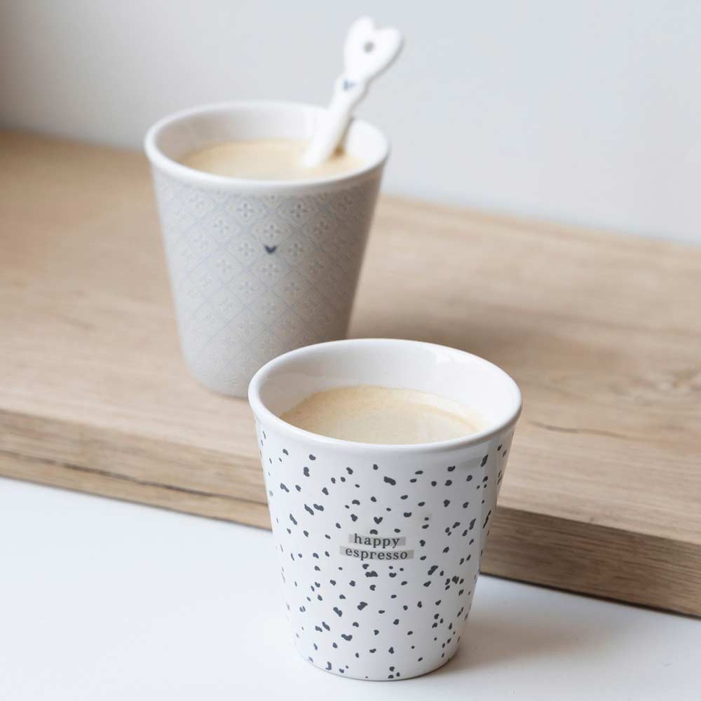 Zwei Bastion-Kollektionen – Espresso-Tassen im Paperlook Little Love mit einem Löffel auf einem Holztisch.