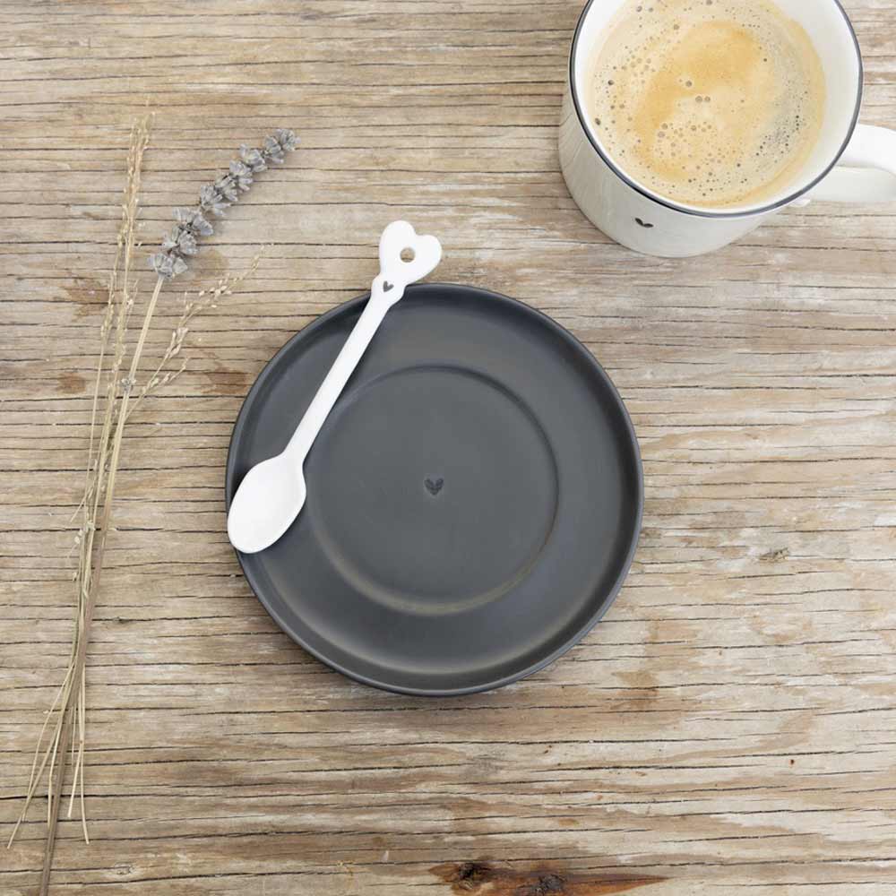 Eine Tasse Kaffee und ein Löffel mit einem Bastion Collections – Löffel für Kaffee Herz weiß Muster auf einem Holztisch.