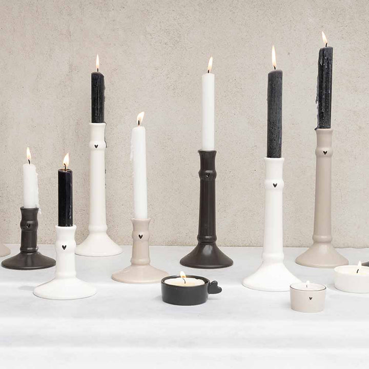 Eine Gruppe von Bastion Collections – Kerzenständer für Stabkerze Herz 24 cm auf einem Tisch mit schwarzen und weißen Kerzen.