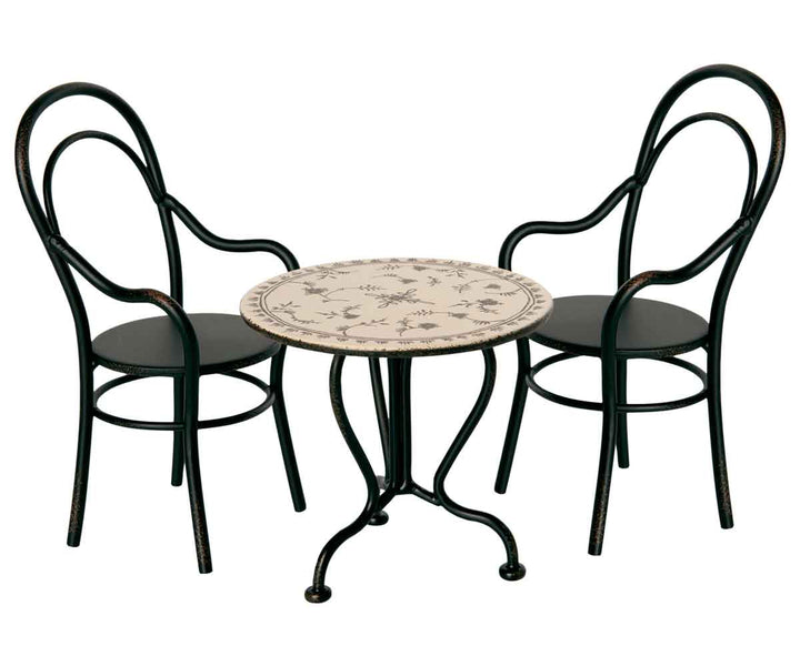 Ein Maileg-Bistro-Set mit zwei Metallstühlen und einem kleinen runden Tisch mit dekorativer Platte.