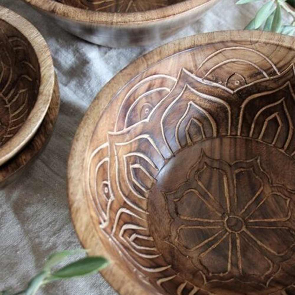 Geschnitzte Holzschüsseln mit komplizierten Mustern auf einem strukturierten Stoff „Majas Cottage - Schüssel Fleur groß“.
