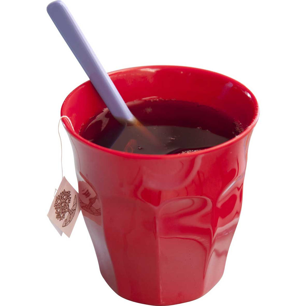 Red Rice - Melaminbecher Rot Medium mit Tee, einem blauen Löffel darin und einem über den Rand hängenden Teebeuteletikett auf weißem Hintergrund.