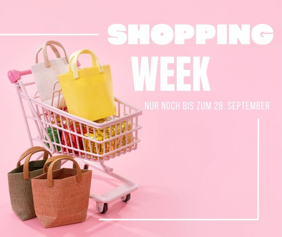 Ein rosafarbener Einkaufswagen mit bunten gewebten Taschen und eingewickelten Süßigkeiten vor einem rosafarbenen Hintergrund. Der Text lautet: "Shopping Week, nur noch bis zum 28. September.