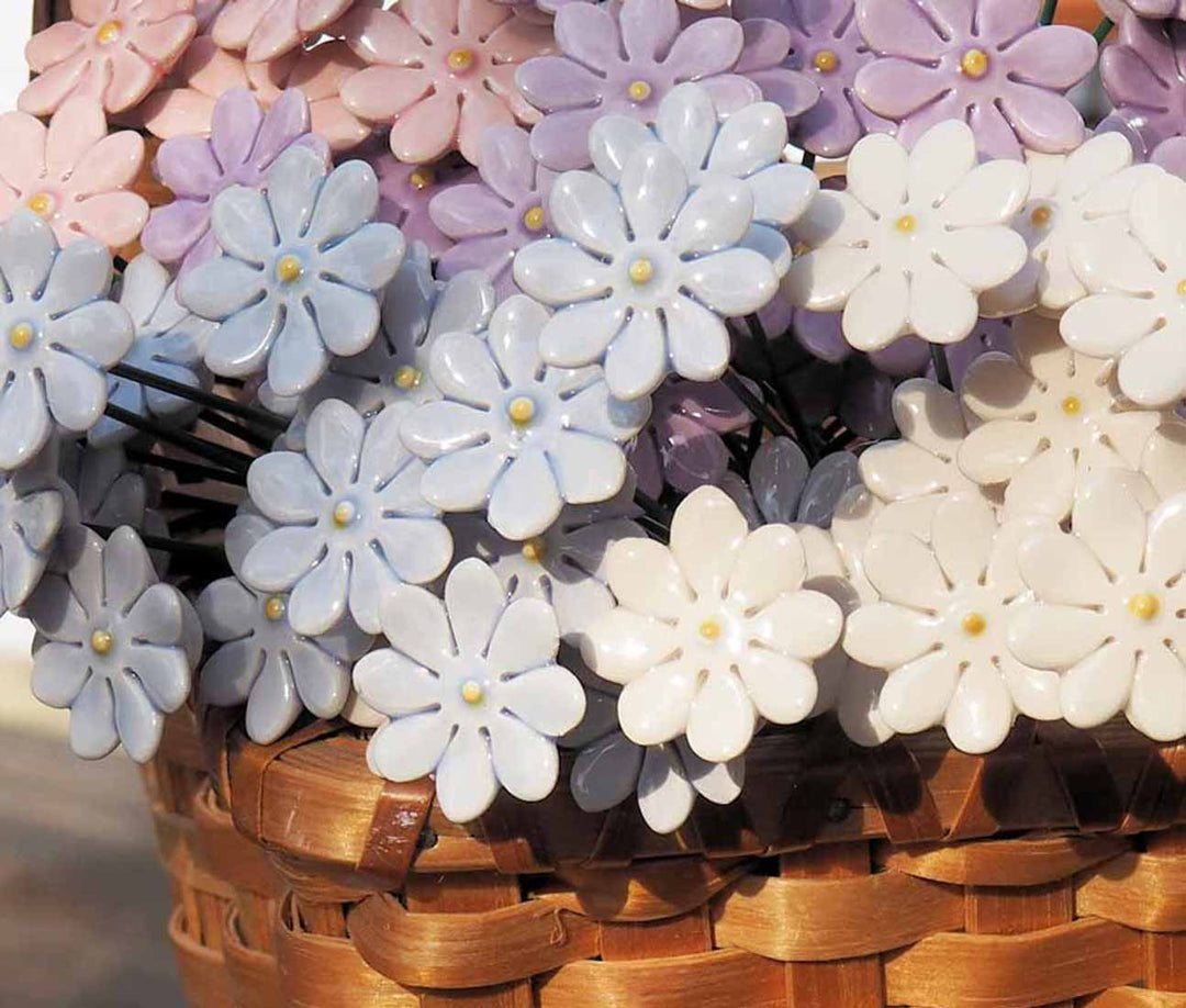 Nahaufnahme eines Weidenkorbs gefüllt mit zarten Kunstblumen in den Farben Rosa, Blau und Weiß.