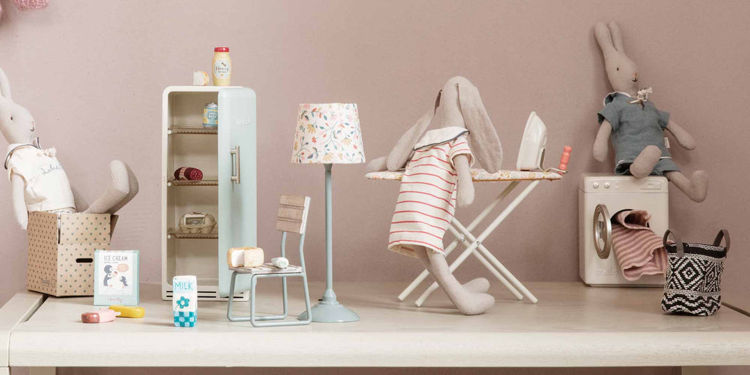 Miniatur-Kinderspielbereich mit Plüschtieren, die Hausarbeiten erledigen, darunter Bügeln und Wäschewaschen.
