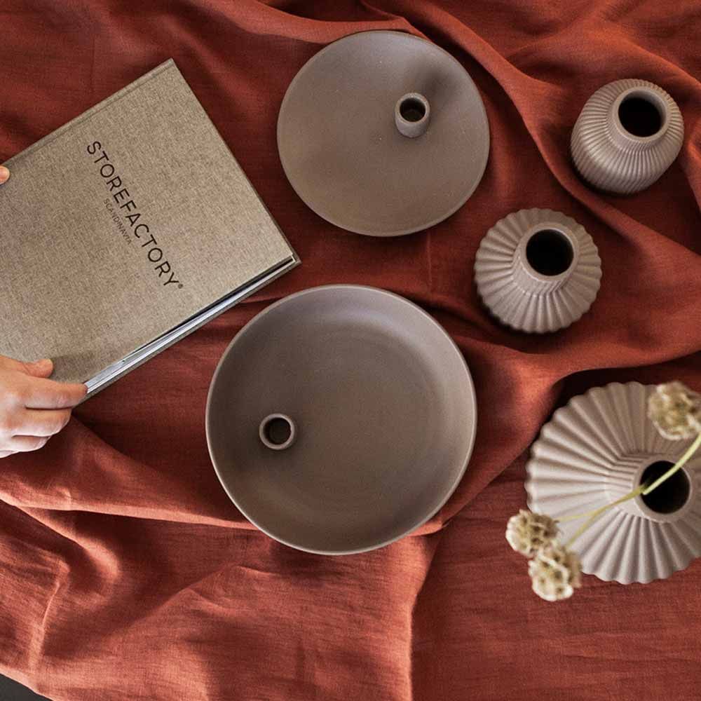 Braune Lidatorp-Kerzenschalen von Storefactory mit Vasen auf rostfarbenem Stoff, von oben fotografiert