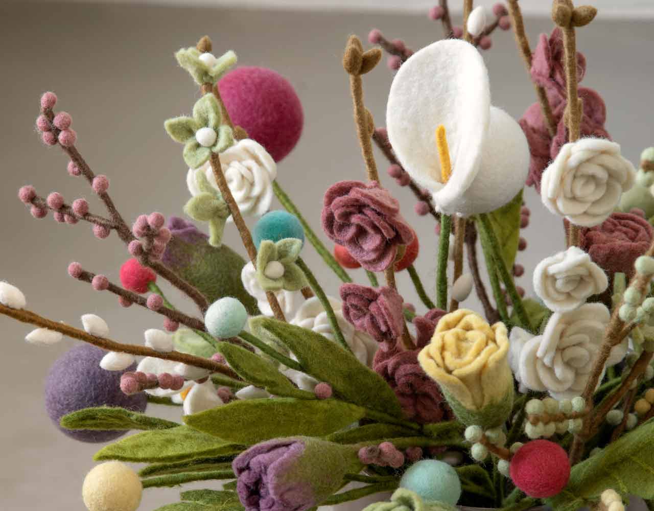 Filzblumen in einer Vase auf einem Tisch.