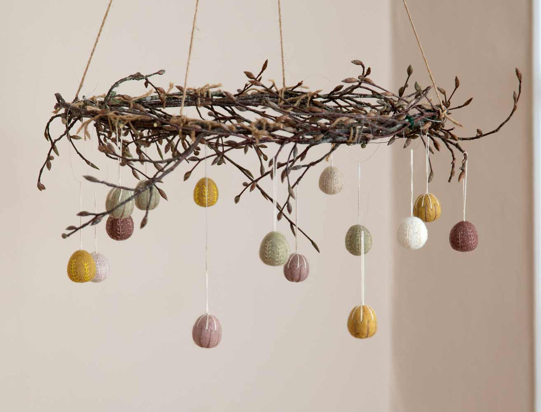 Ein handgefertigtes Mobile mit bunten, strukturierten Kugeln, die an einem Ast hängen.