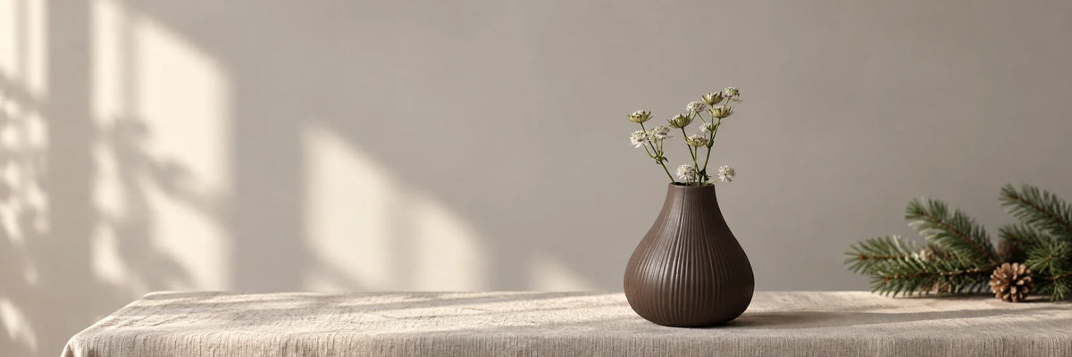 Braune gerillte Ekenäs-Vase von Storefactory mit zarten Blumen auf einem hellen Tisch