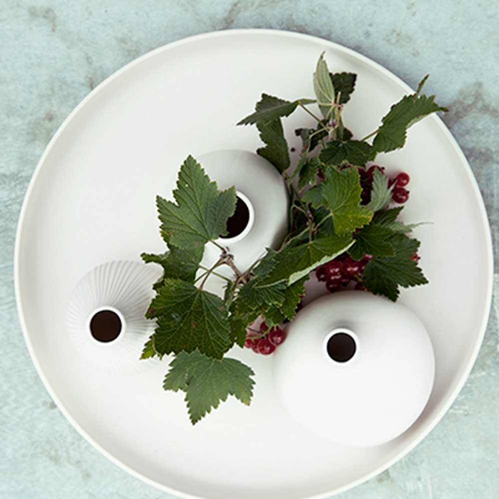 Weißes rundes Tablett Grimshult mit weißen Vasen und grünen Zweigen mit roten Beeren