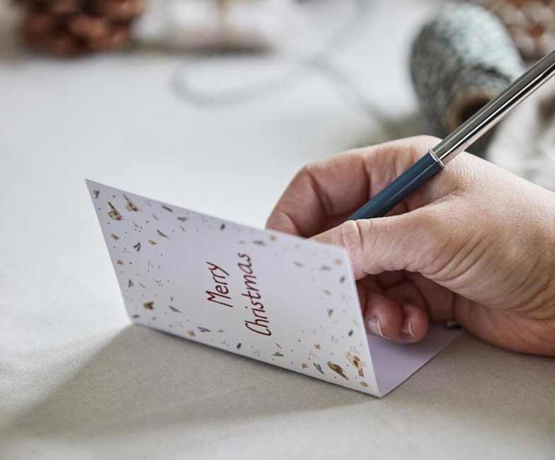 Weihnachtskarte wird mit Kulli beschriftet