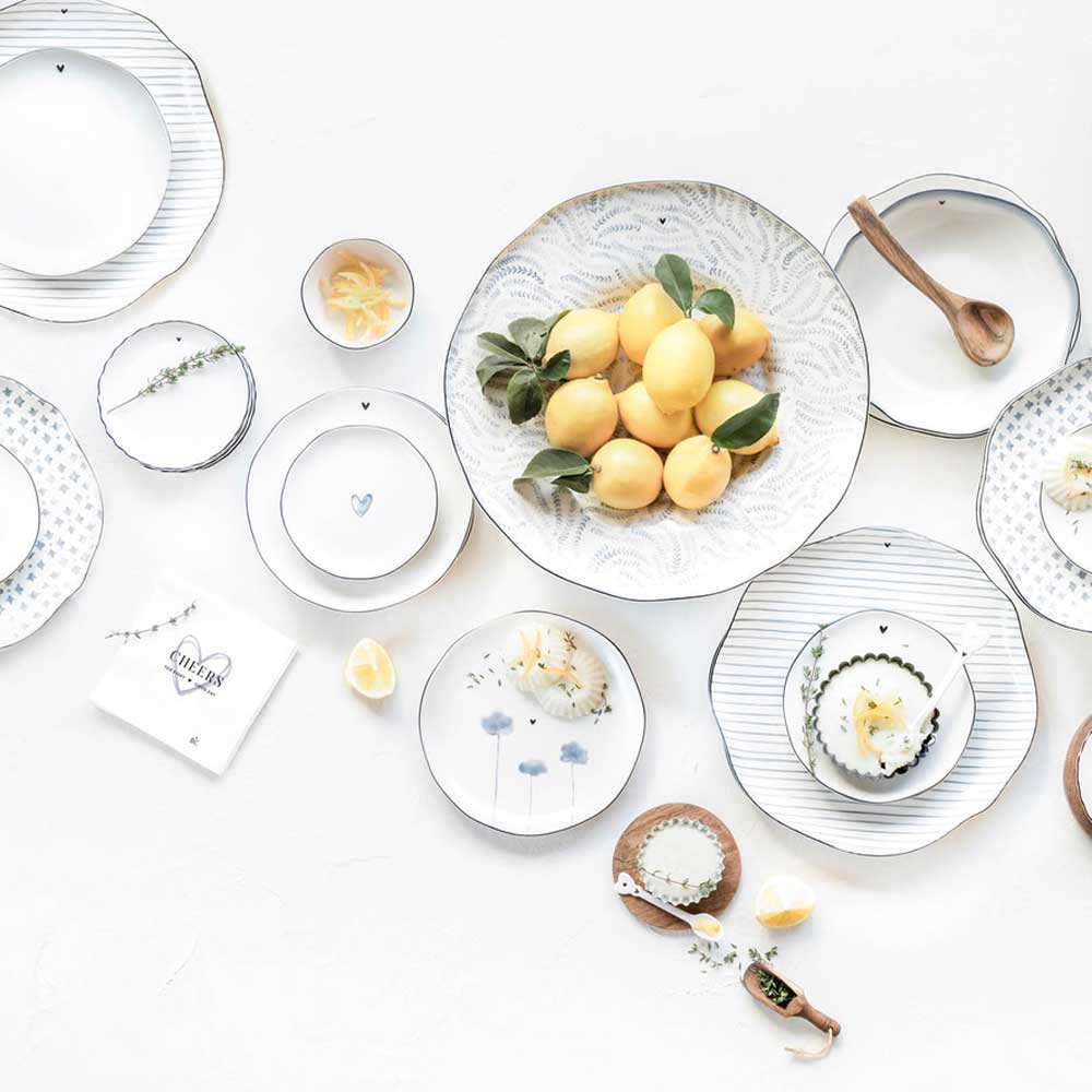 Eine elegant arrangierte Tischdekoration mit Tellern, Besteck und einer Schüssel der Bastion Collection – Tasse Iris Blue Poppy auf weißem Hintergrund.