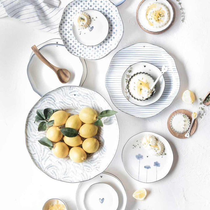 Eine Draufsicht auf einen gedeckten Tisch mit Bastion Collections – Dessertteller Iris Blue Poppy-Tellern, Zitronen und weichgekochten Eiern, arrangiert in einem leichten, minimalistischen Stil.