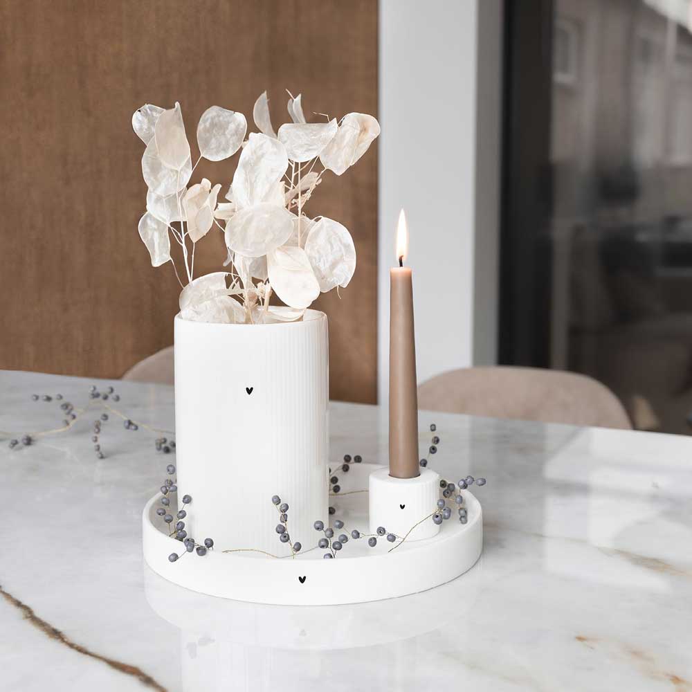 Eine weiße Vase mit einer Kerze auf einem Marmortisch, ein Highlight der Bastion Collections – Kerzenhalter Herz für Stabkerze mit Rillen.