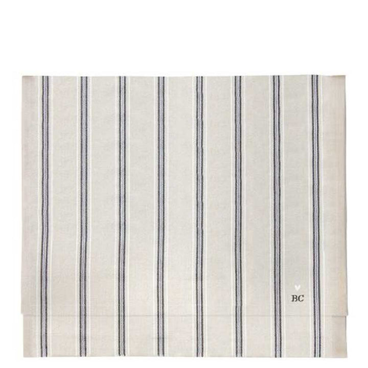 Ein beiger Tischläufer mit vertikalen schwarzen Streifen und „BC“ in der unteren rechten Ecke von Bastion Collections, Maße 160 x 50 cm.