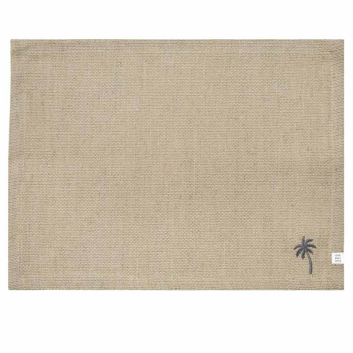 Ein Tischset von Bastion Collections aus beigefarbenem gewebtem Leinen mit einer kleinen gestickten Palme in der unteren rechten Ecke, Maße 48 x 36 cm.