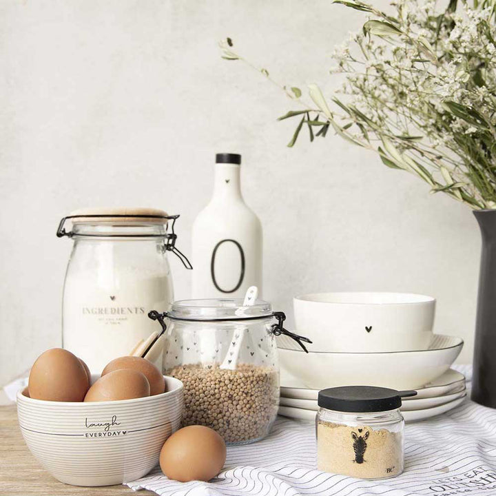 Ein Tisch mit Bastion Collections - Vorratsglas Happy & Ingredients, Schüsseln, Tellern und Eiern.
