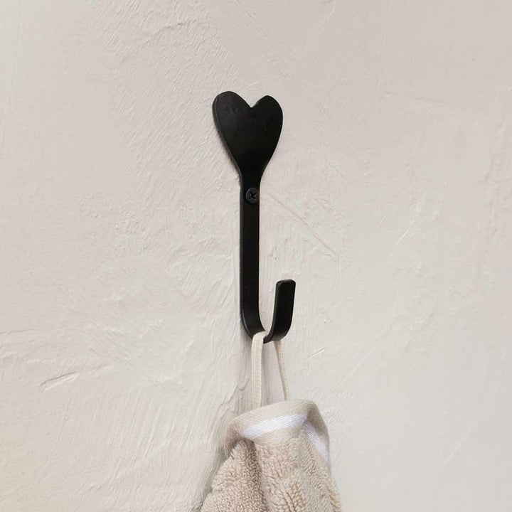 Ein schwarzer Bastion Collections - Wandhaken Herz schwarz mit einem daran hängenden Handtuch.