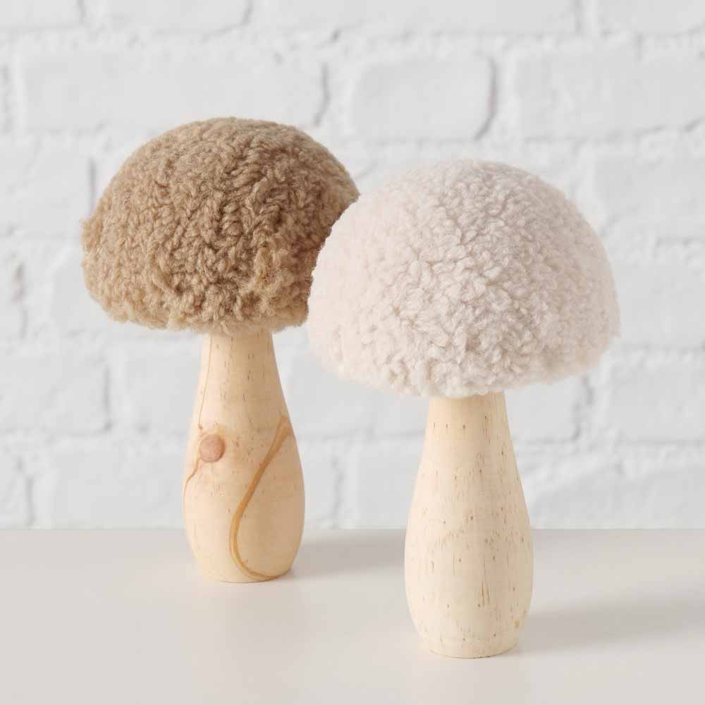 Zwei Boltze Pilz Deko Teddy-Ornamente mit flauschigen, strukturierten Oberseiten in Braun und Weiß, auf einer flachen Oberfläche vor einer weißen Ziegelwand platziert.