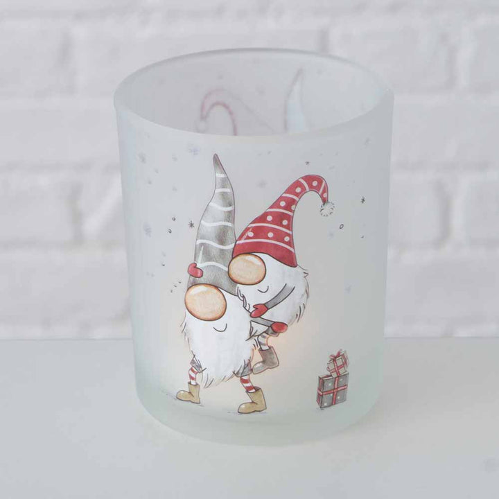 Das Boltze - Windlicht Wichtel Bambi 2er-Set umfasst Kerzenhalter aus Milchglas mit festlichen Wichtelmotiven mit roten und grauen Hüten, die jeweils Geschenke halten.