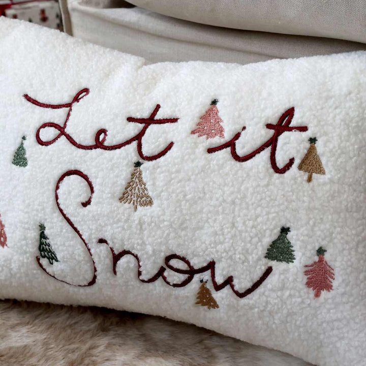 Chic Antique - Kissenbezug „Let It Snow“ Weiß mit rot gesticktem Text, verziert mit bunten kleinen Baummotiven.