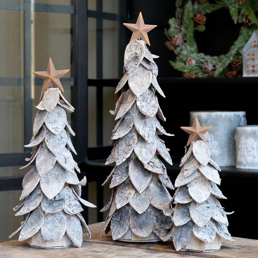 Ein Set aus drei Chic Antique - Weihnachtsbaum mit Stern, mit geschichteten blattähnlichen Mustern und Sternspitzen, wunderschön präsentiert auf einer Tischplatte.