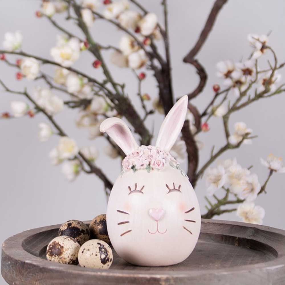 Eine Figur von Clayre & Eef - Hase als Osterei sitzt auf einem Holztablett mit Eiern.