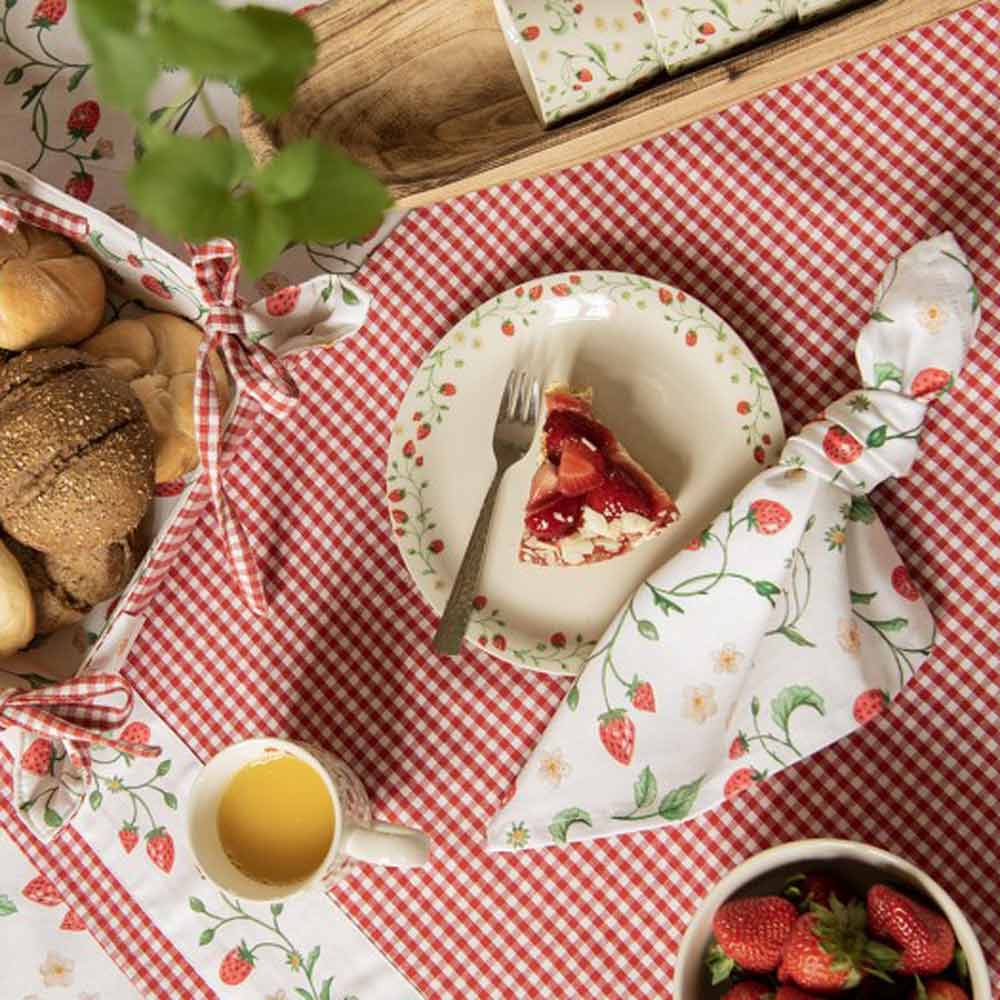 Ein Teller mit einem Stück Kuchen und einer Gabel auf der Clayre & Eef - Tischdecke Erdbeere Länge: 100 cm, Breite: 100 cm.