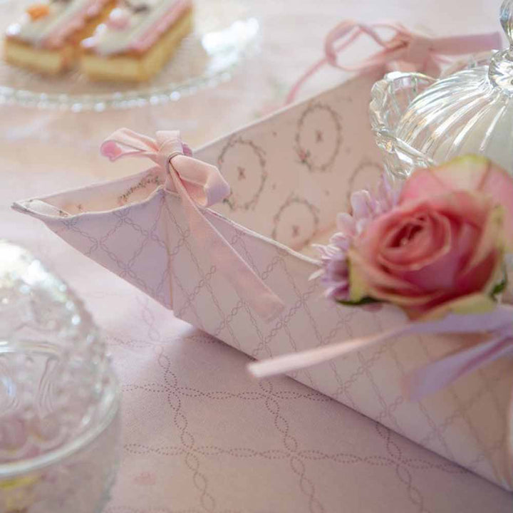 Ein rosa Clayre & Eef - Ofenhandschuh Hase Rosa mit Blumen und einem Glasgefäß auf einem Tisch.