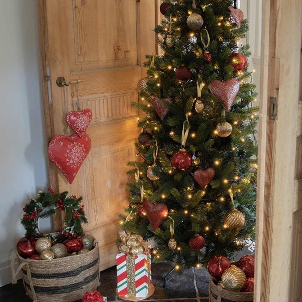 Ein geschmückter Weihnachtsbaum mit Lichtern, rot und gold marmorierten Ornamenten (Ø 7 cm) von Clayre & Eef, umgeben von Geschenktüten, Kränzen und einem roten herzförmigen Wandbehang.