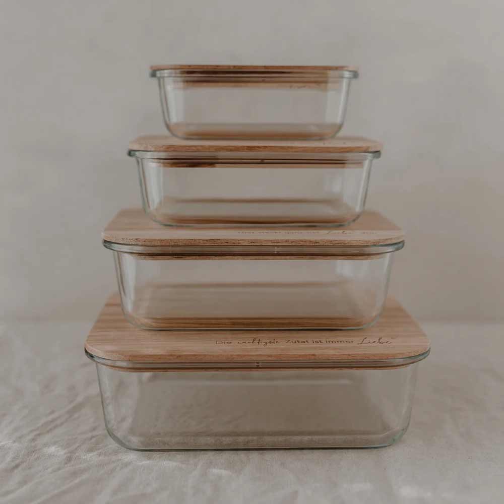 Vier Eulenschnitt Vorratsbehälter aus Glas mit Holzdeckel und Spruch sind übereinandergestapelt vor hellem Hintergrund.