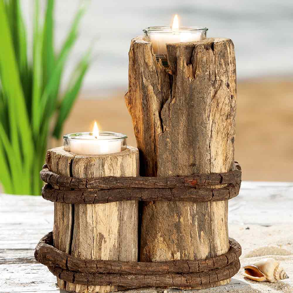 Zwei Gilde Maritime Teelichthalter aus Treibholz mit Glas, die jeweils ein brennendes Teelicht halten, werden auf gestapelten Treibholzstämmen mit einem Ast präsentiert, die auf einer weißen Holzoberfläche angeordnet sind.