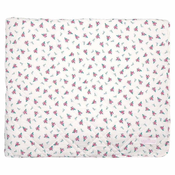 Abgebildet ist ein GreenGate - Jalia Quilt in Weiß mit einem Blumenmuster aus kleinen rosa und grünen Blumen. In einer Ecke des Quilts ist ein kleines Stoffetikett aufgenäht.