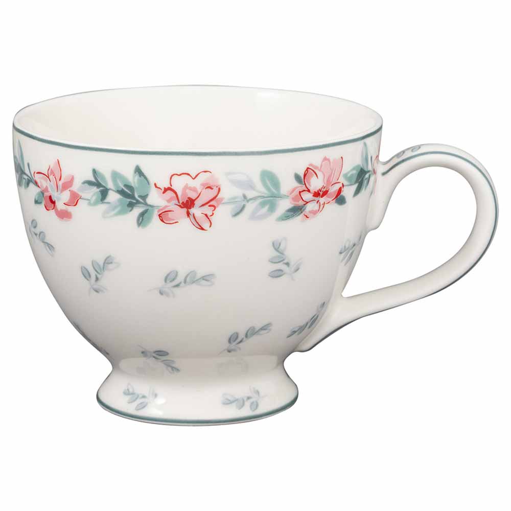 Eine GreenGate - Jalia Teetasse in Weiß mit grünem Rand, geschmückt mit einem Muster aus roten Blumen und grünen Blättern.