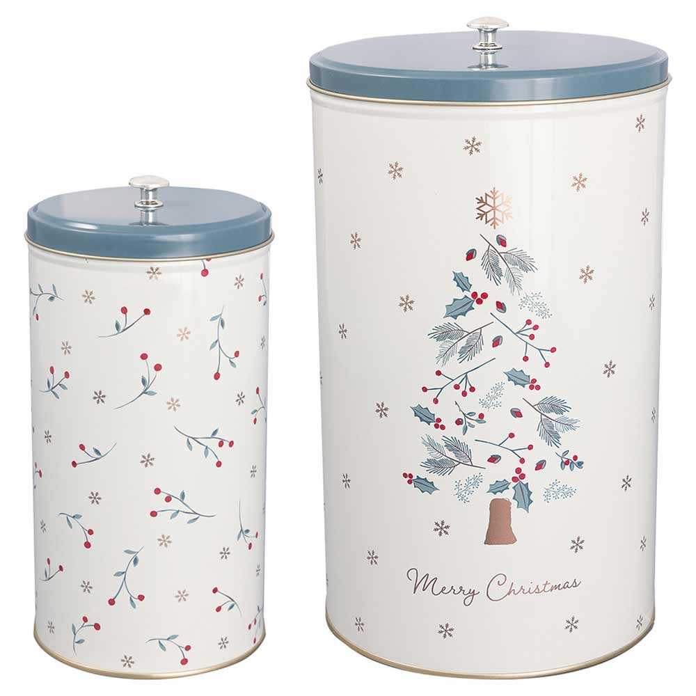 Zwei weiße zylindrische Behälter mit blauen Deckeln; der größere hat ein Weihnachtsbaumdesign und den Text „Frohe Weihnachten“, der kleinere ein Beerenmuster - GreenGate - Lucie Xmas runde Metalldosen weiß 2er-Set.