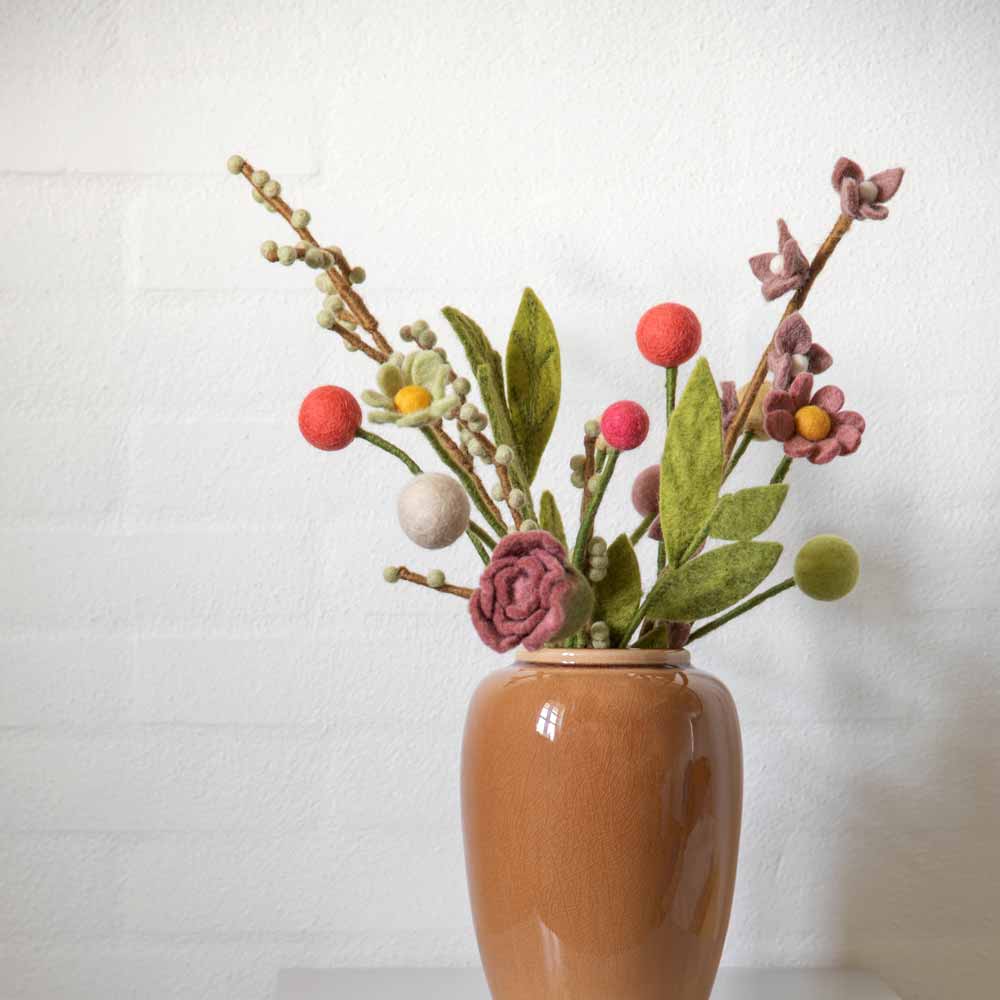 Eine Vase mit einem Arrangement aus Gry & Sif - Blume Filz Ø3 Blumen und Dekorationen vor einer weißen Wand.