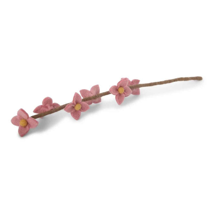 Ein einzelner Zweig mit kleinen rosa Blüten von Gry & Sif - Blumen auf Stiel Filz vor weißem Hintergrund.