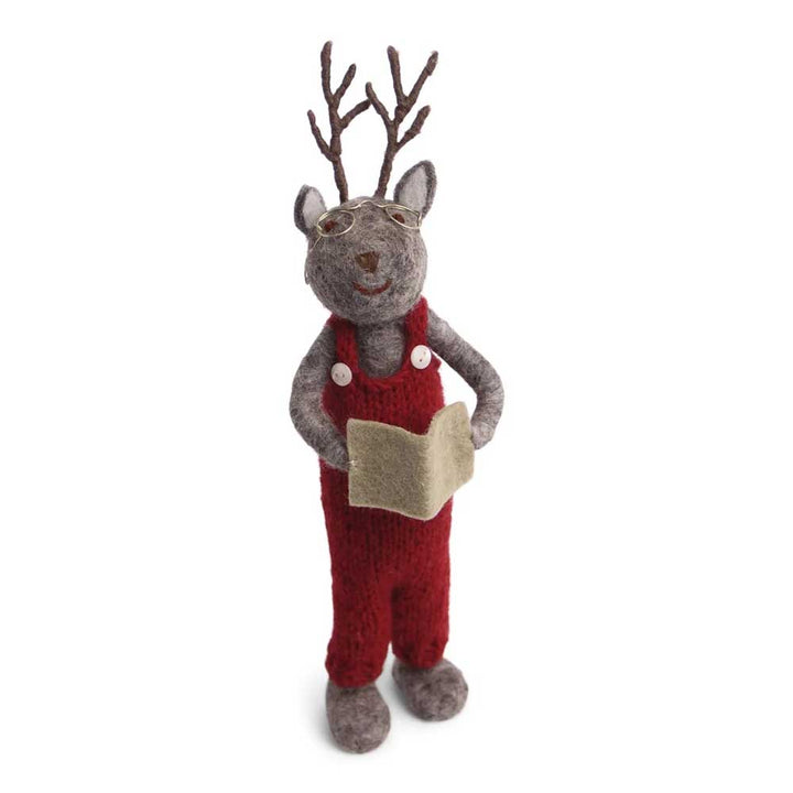 Eine Filzfigur eines Rentierjungen mit Geweih und Brille, in ein rotes Outfit gekleidet und ein kleines beiges Buch haltend. Produktname: Gry &amp; Sif - Rentier Junge mit Buch.