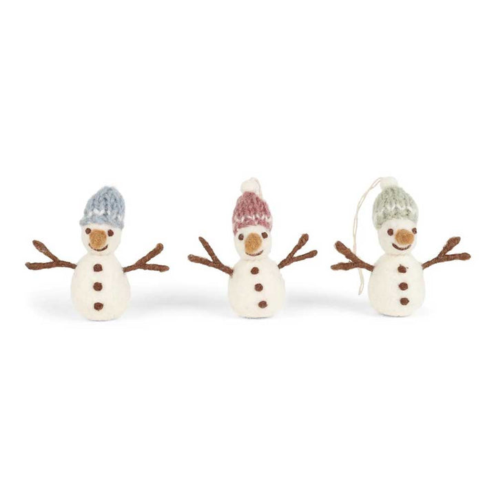 Drei Filz-Schneemänner mit Stabarmen und Knopfdetails, die jeweils eine gemütliche Strickmütze in Blau, Rot und Grün tragen, stehen in einer Reihe. Dieses entzückende Trio ist Teil der Gry &amp; Sif - Anhänger Schneemänner mit Wollmützen Filz 3er-Set-Kollektion.
