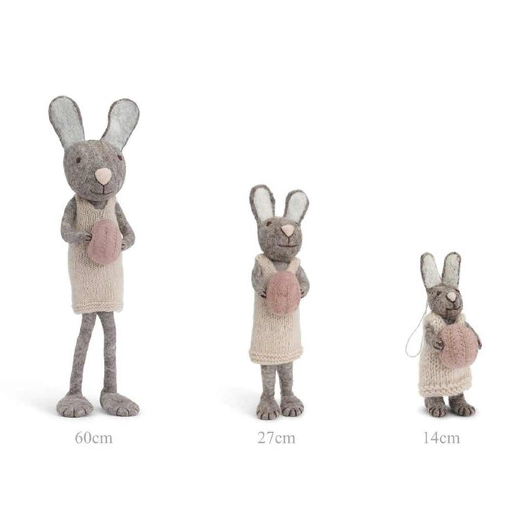 Drei hellgraue Gry & Sif - Hase Filz mit Ei-Kaninchen abnehmender Größe, die in einer Reihe stehen und jeweils eine Karotte halten. Ihre Körpergrößen sind mit 60 cm, 27 cm bzw. 14 cm angegeben.