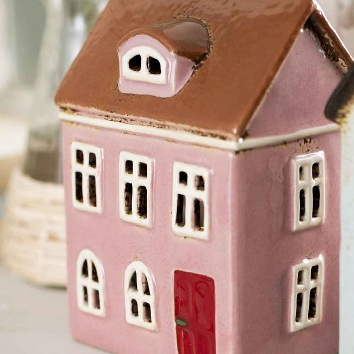 Ein kleines Keramikmodell eines Ib Laursen – Hauses für Teelicht Nyhavn gerundete Dachfenster mit braunem Dach, weißen Fensterrahmen und einer roten Tür.